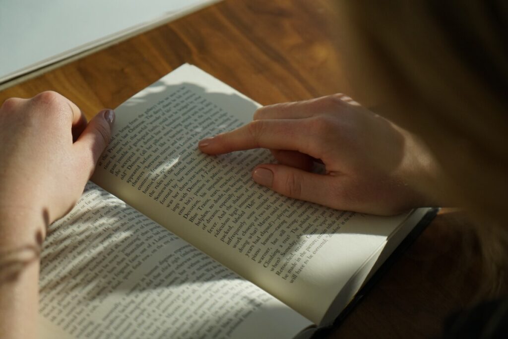 a person's hand on a book while reading